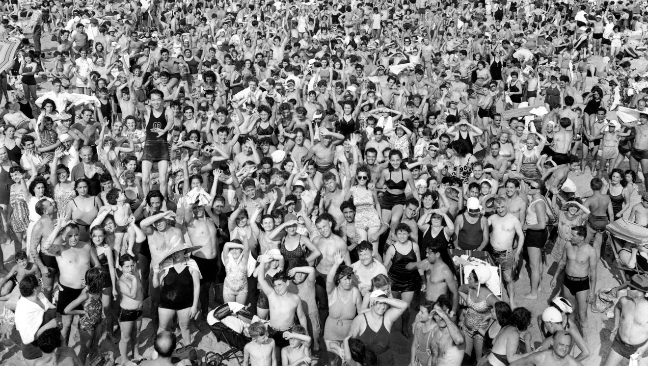 Large crowd of people raising hands at an outdoor event.