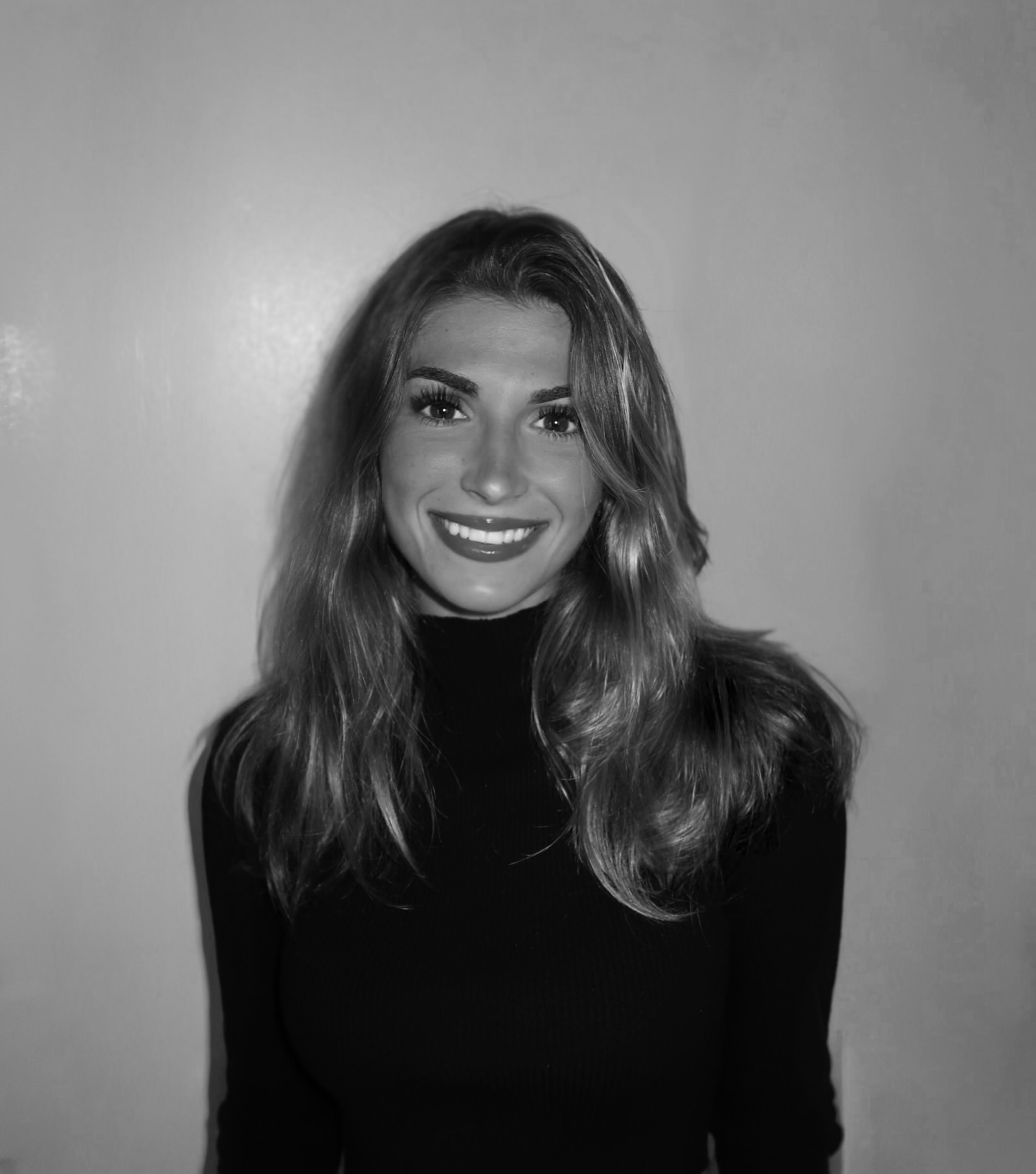 Black and white portrait of a smiling woman with wavy hair in a dark top.