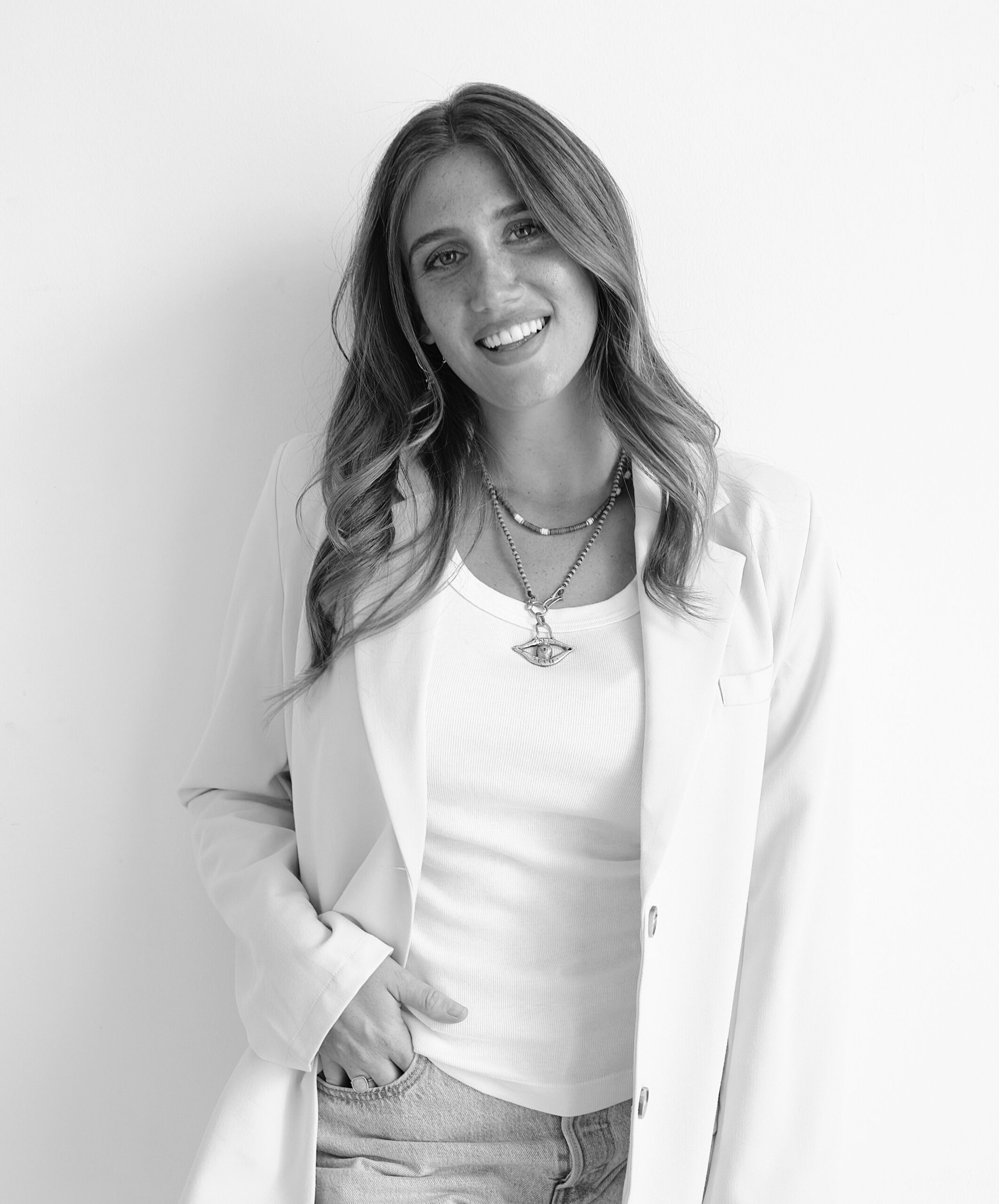 Smiling woman in a white blazer and top.