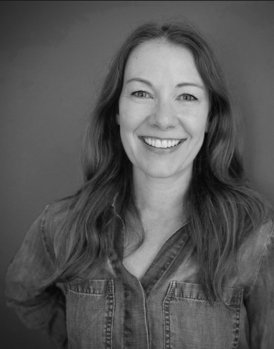 Smiling woman with long hair in a black and white portrait.