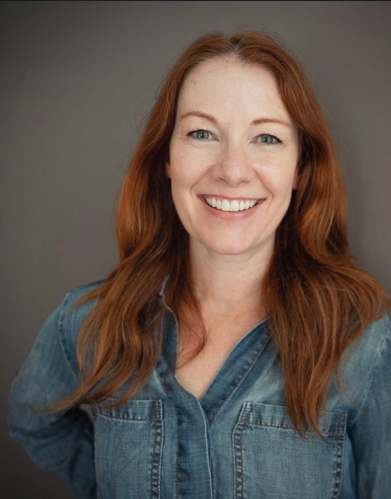 Smiling red-haired woman in a casual blue shirt.