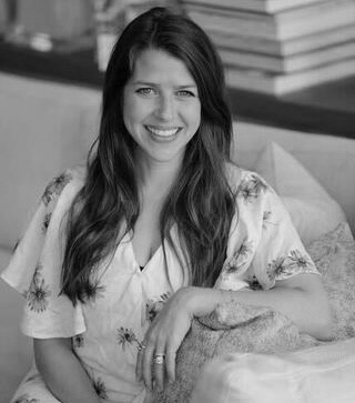 Smiling woman with long hair sitting comfortably indoors.