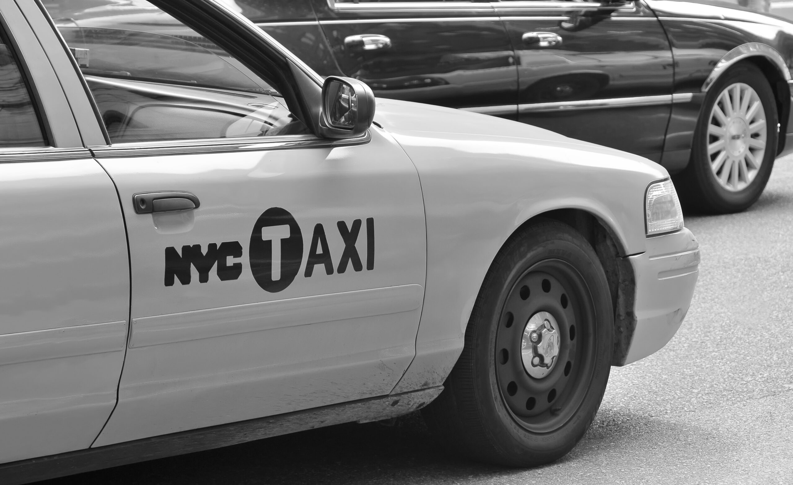 Classic NYC yellow taxi parked on the street in black and white.
