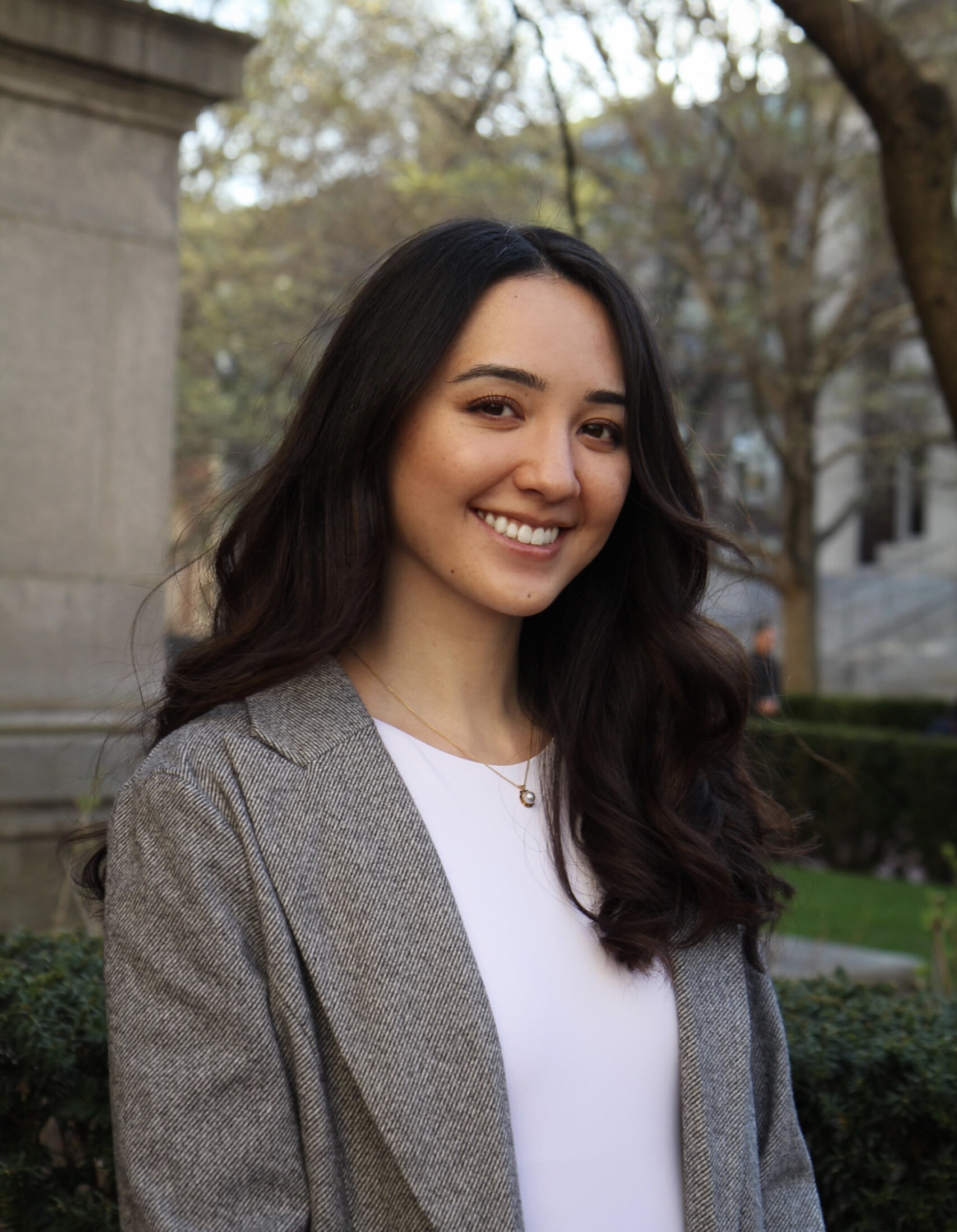 Young woman smiling outdoors in professional attire.